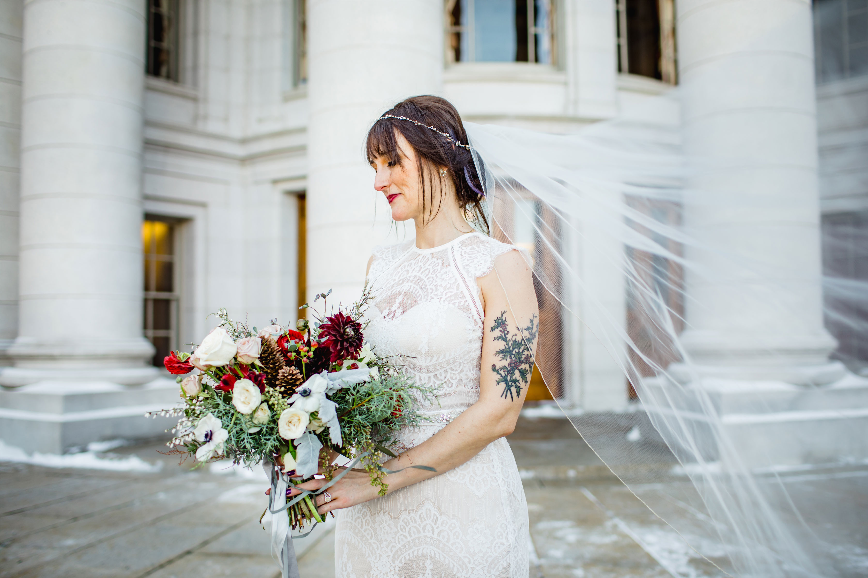 Alluring Blooms Madison WI bride holding a winter inspired bouquet on the steps of the state capitol building with veil blowing in the wind